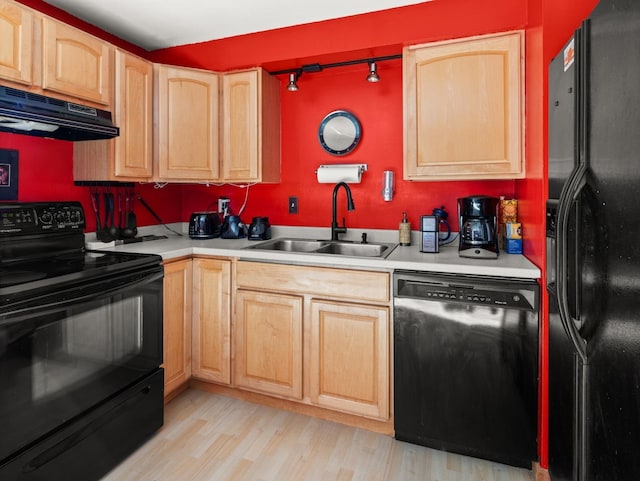 kitchen with light wood-style flooring, under cabinet range hood, a sink, light countertops, and black appliances