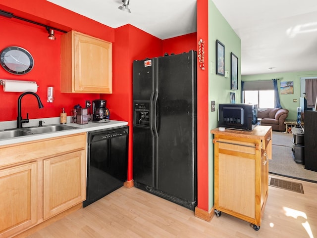 kitchen with a sink, black appliances, light countertops, and visible vents