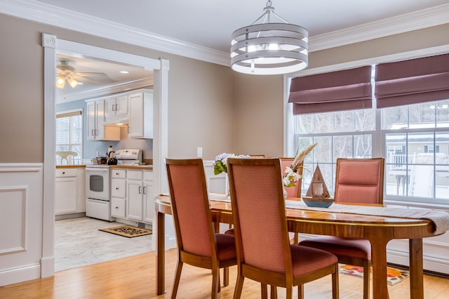 dining area with light wood finished floors and crown molding