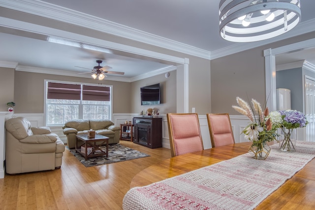 dining room featuring light wood-type flooring, ornamental molding, and wainscoting