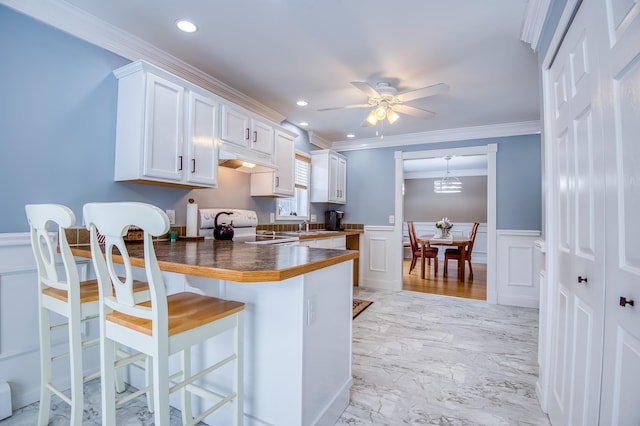 kitchen featuring dark countertops, electric range oven, white cabinets, a peninsula, and a kitchen breakfast bar