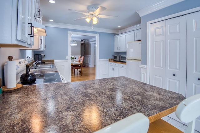 kitchen with dark countertops, freestanding refrigerator, and crown molding