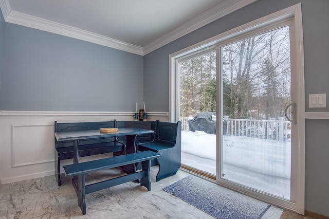 dining room with marble finish floor, ornamental molding, and a wainscoted wall