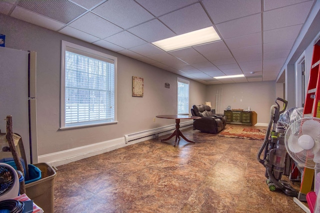 office space with a baseboard heating unit, a paneled ceiling, visible vents, and baseboards