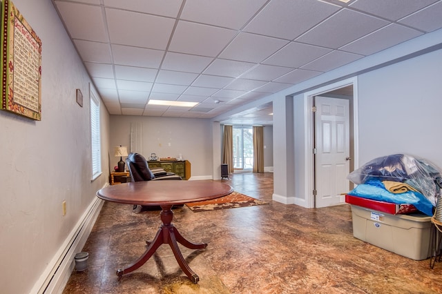 interior space with baseboards, baseboard heating, and a drop ceiling