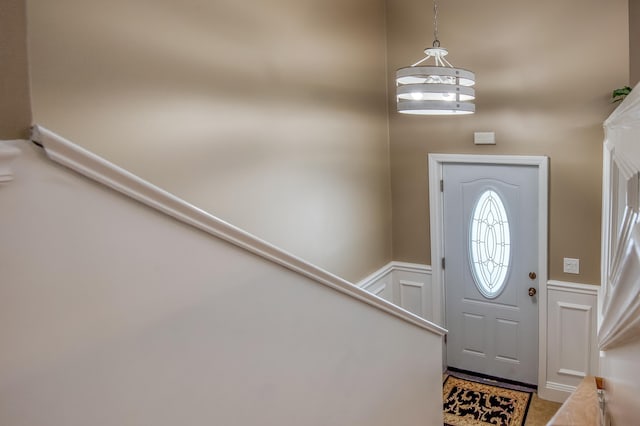 foyer with a wainscoted wall, stairs, and a decorative wall