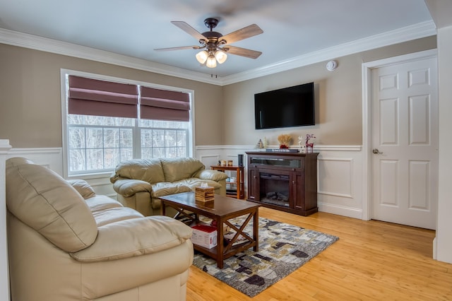 living room featuring wainscoting, light wood-type flooring, and a fireplace