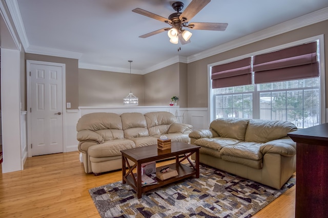 living area featuring wainscoting, light wood-style flooring, and crown molding