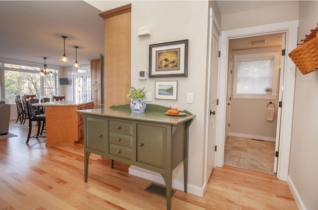 hallway featuring light wood-type flooring, baseboards, and visible vents