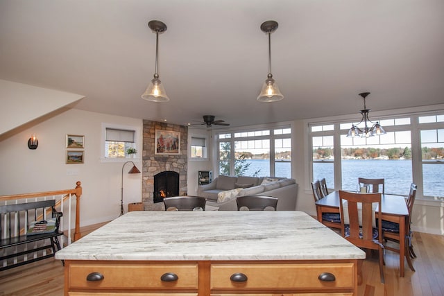 kitchen featuring open floor plan, light countertops, a stone fireplace, and a water view