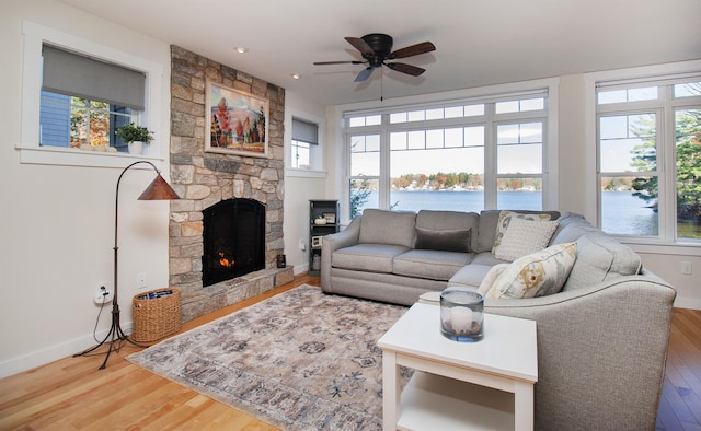 living room with a water view, a fireplace, baseboards, and wood finished floors