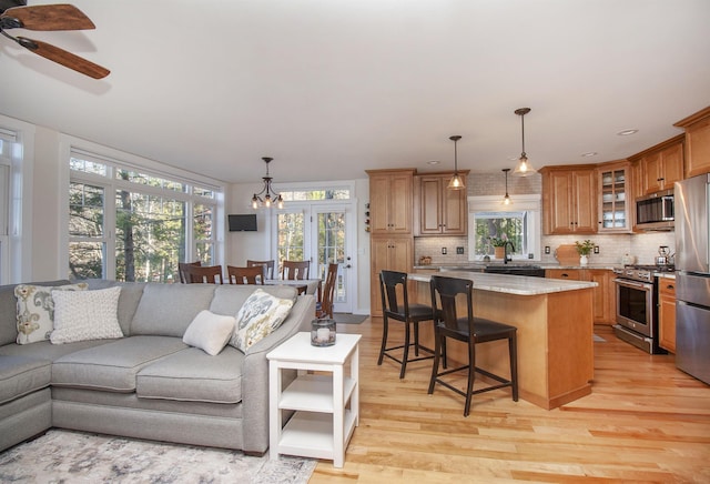 living room featuring ceiling fan with notable chandelier and light wood-style floors