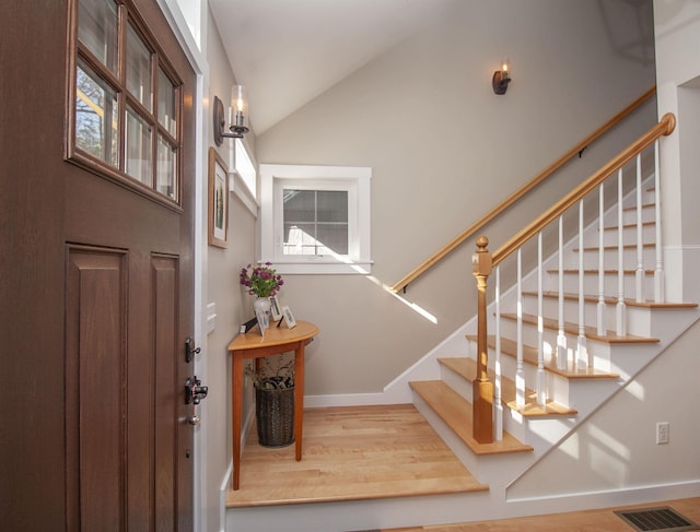 entrance foyer featuring lofted ceiling, wood finished floors, visible vents, and baseboards