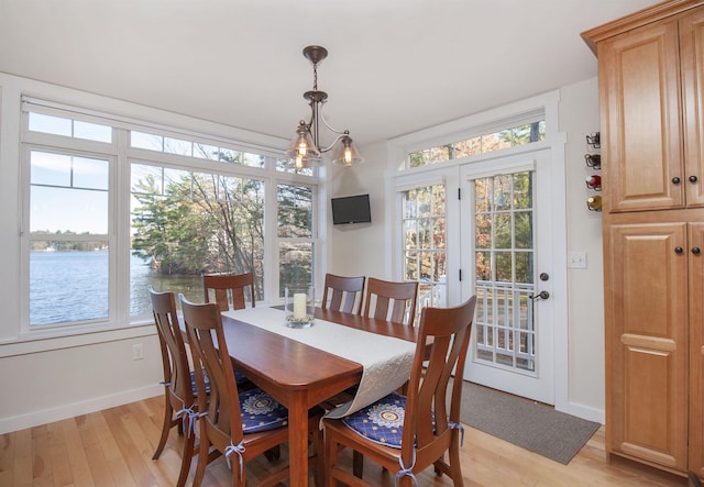 dining room featuring a water view, a wealth of natural light, and light wood-style floors