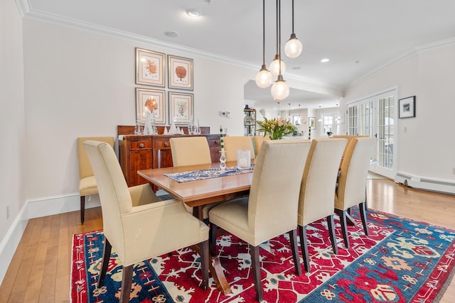 dining room featuring light wood finished floors, ornamental molding, and a baseboard radiator