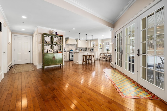 hall featuring crown molding, baseboard heating, wood finished floors, and french doors