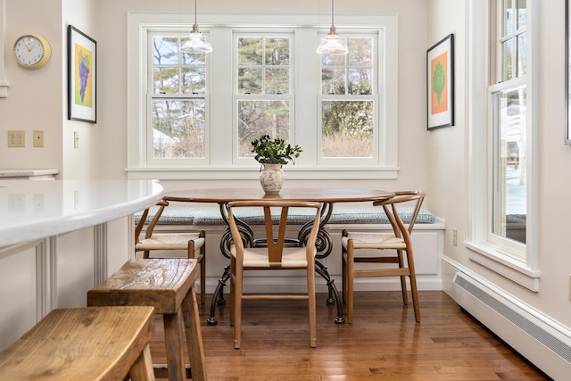 dining space with a baseboard heating unit, baseboards, breakfast area, and wood finished floors