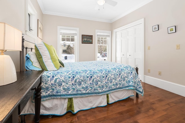 bedroom featuring baseboards, dark wood finished floors, ceiling fan, ornamental molding, and a closet