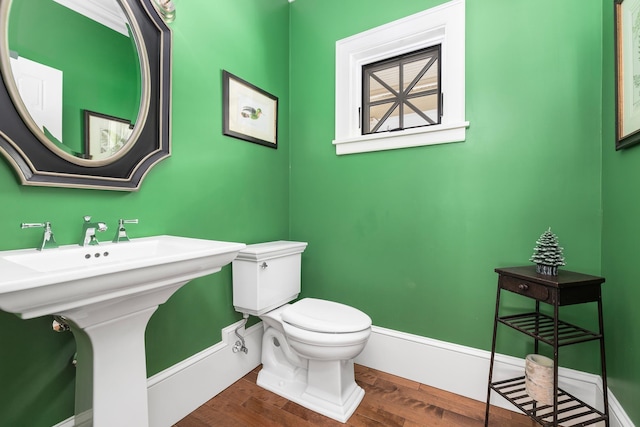 half bath featuring toilet, baseboards, and wood finished floors