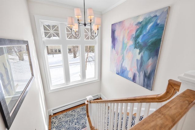 stairs with a notable chandelier, a baseboard heating unit, and crown molding