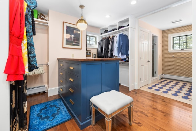 spacious closet with a baseboard heating unit, visible vents, and dark wood-style floors