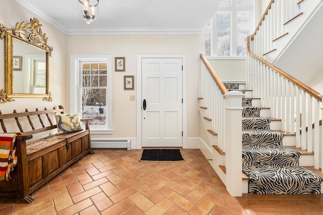 foyer entrance with a baseboard heating unit, brick floor, crown molding, and stairway