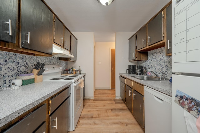 kitchen with light countertops, a sink, dark brown cabinets, white appliances, and under cabinet range hood