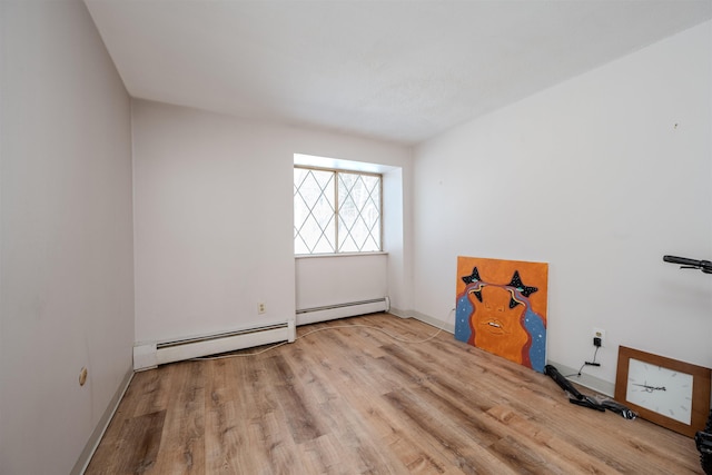 spare room featuring light wood-style floors, baseboards, and baseboard heating