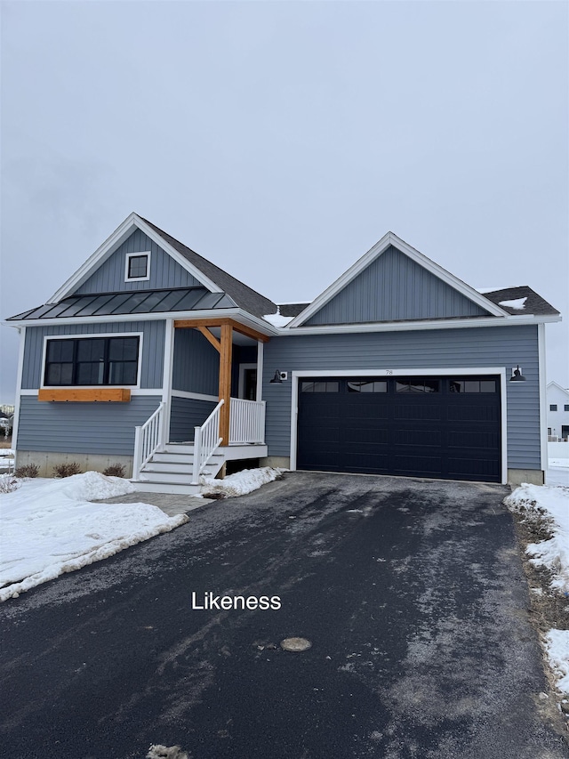 view of front facade with an attached garage, a standing seam roof, metal roof, and aphalt driveway