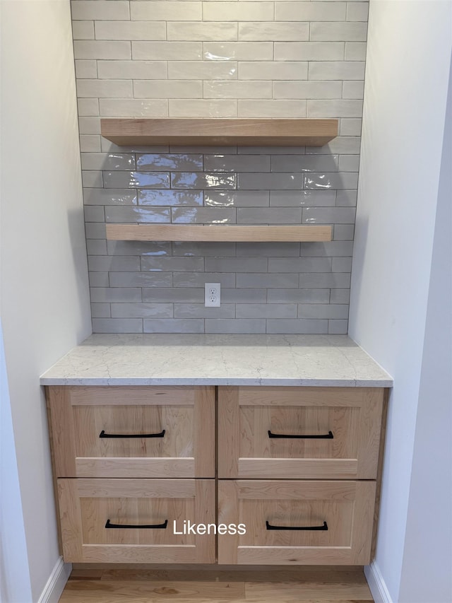 interior details featuring tasteful backsplash, wood finished floors, and baseboards