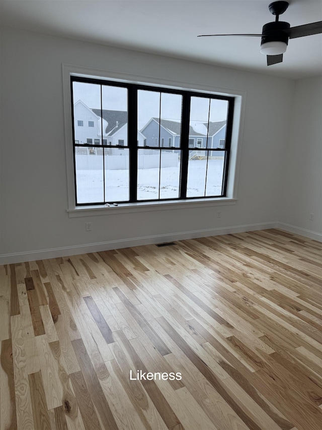 empty room featuring light wood-style floors, visible vents, baseboards, and a ceiling fan