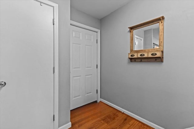 hallway featuring wood finished floors and baseboards