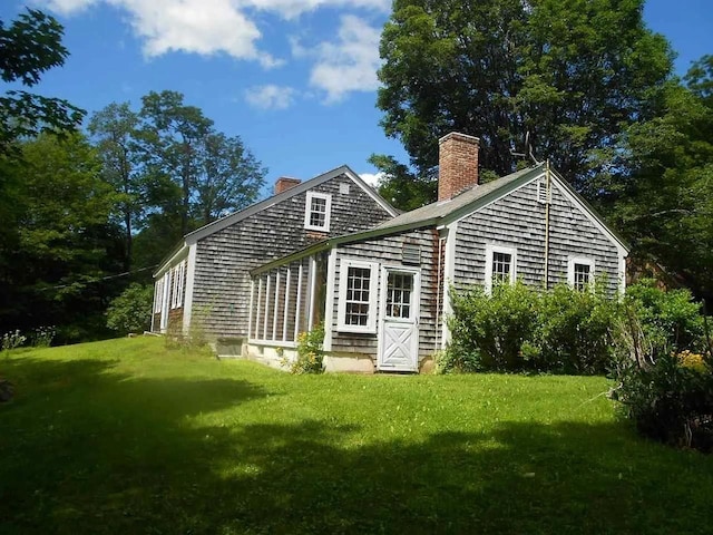 back of property with a yard and a chimney