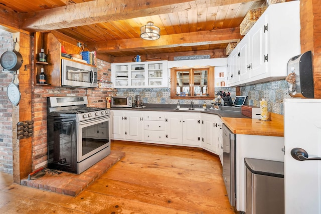 kitchen featuring glass insert cabinets, appliances with stainless steel finishes, white cabinets, and a sink