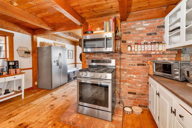 kitchen with stainless steel appliances, white cabinetry, light wood-style floors, light countertops, and beamed ceiling