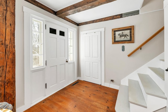 entryway featuring visible vents, baseboards, light wood-style floors, stairway, and beam ceiling