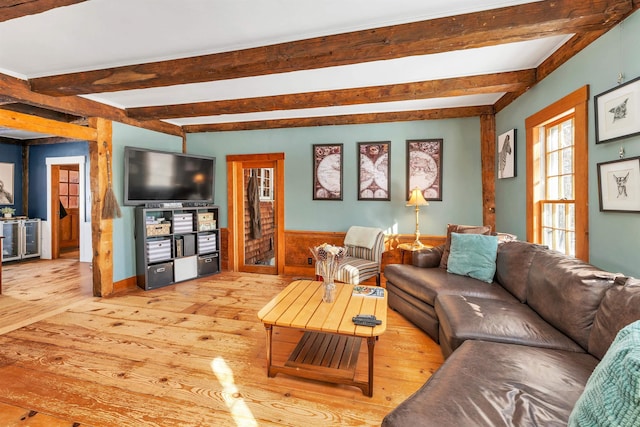 living area with a wainscoted wall, beamed ceiling, and wood finished floors