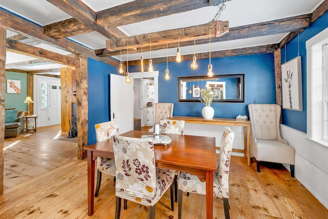 dining space with light wood-style flooring and beamed ceiling