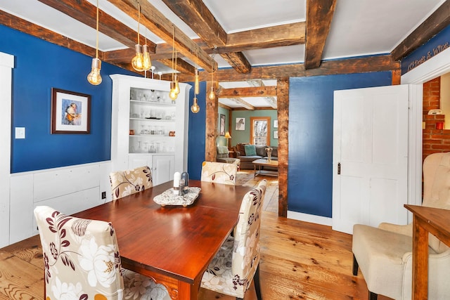 dining area featuring light wood finished floors and beamed ceiling