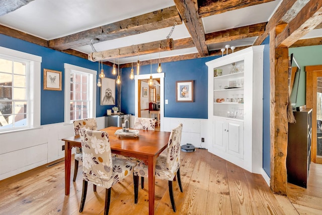 dining room featuring light wood-style floors and beamed ceiling