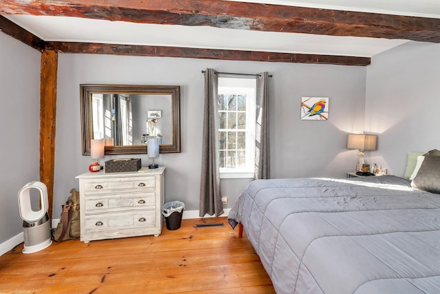 bedroom with beam ceiling, light wood-style flooring, and baseboards