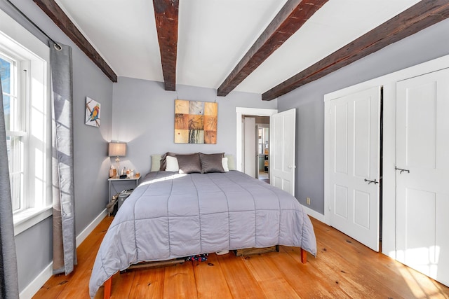 bedroom featuring baseboards, multiple windows, and light wood-style floors