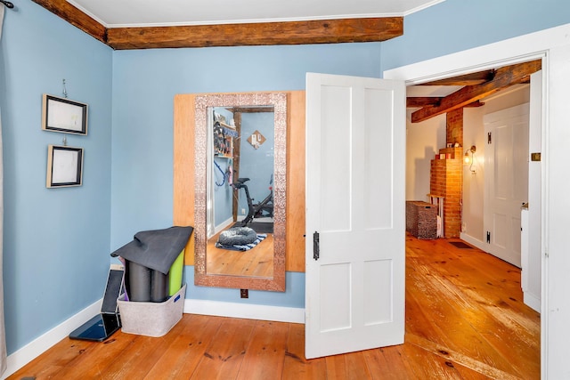 corridor featuring beamed ceiling, wood finished floors, and baseboards