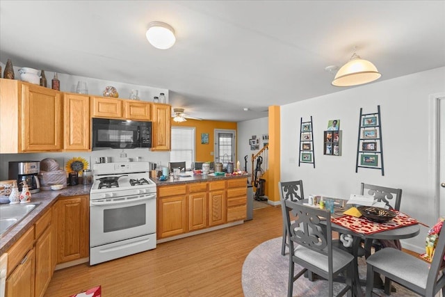 kitchen featuring light wood-style floors, ceiling fan, white gas range oven, and black microwave