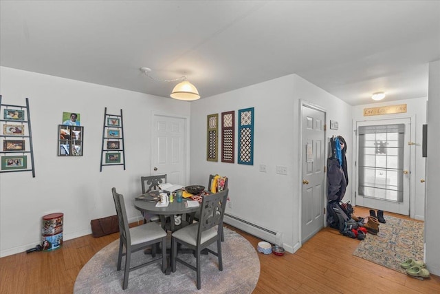 dining space with baseboard heating, wood finished floors, and baseboards