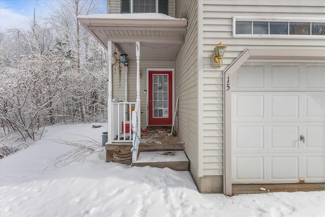 snow covered property entrance with a garage