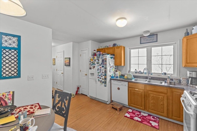 kitchen featuring dark countertops, white appliances, a sink, and light wood-style flooring