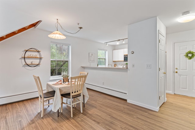 dining area featuring a baseboard radiator, light wood-style flooring, baseboard heating, track lighting, and baseboards