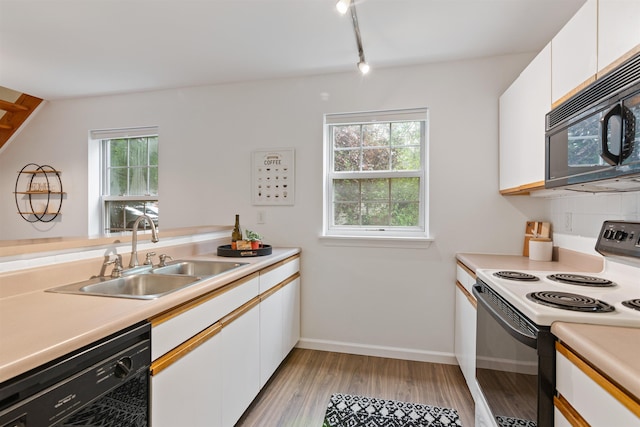 kitchen with a sink, white cabinets, light countertops, black appliances, and light wood finished floors