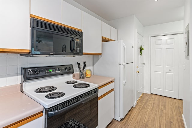 kitchen with black microwave, light countertops, white cabinetry, backsplash, and range with electric stovetop